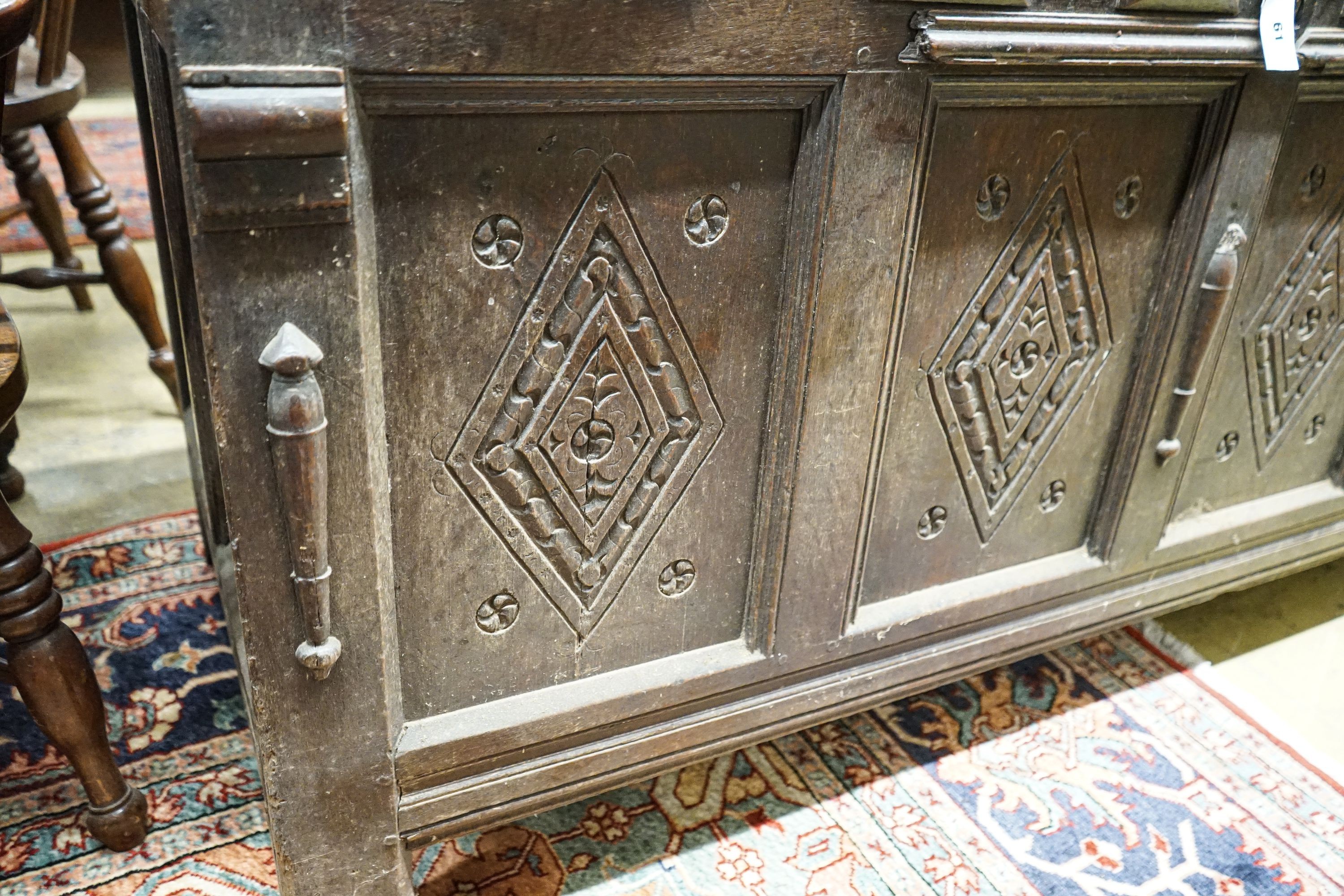 An early 18th century oak coffer, with four panel top and later carved and applied decoration, width 152cm, depth 63cm, height 74cm